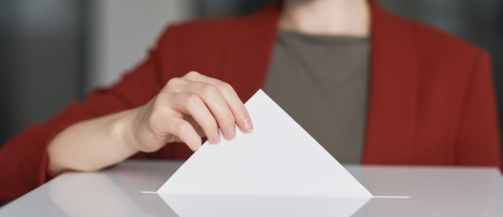 Person casting a vote into a ballot box