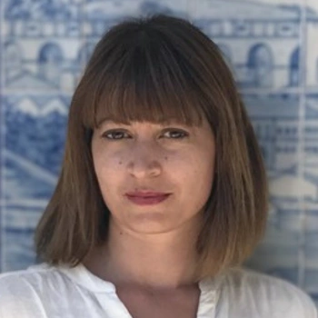 Roula Nezi wearing a white shirt in front of a blue and white tiled wall